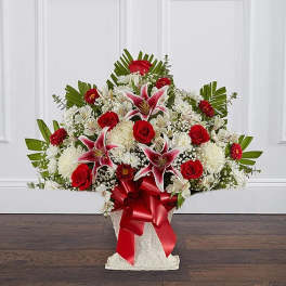 Red roses and white lilies in a white basket with a red ribbon