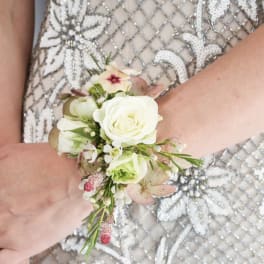 Wrist corsage of white roses and small pink flowers on a beaded dress.