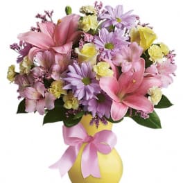 Pink and lavender bouquet in a yellow vase with a pink ribbon
