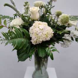 White floral arrangement in a glass vase with roses and hydrangea