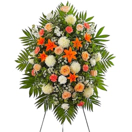 Standing floral spray with peach roses, orange lilies, and white blooms