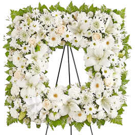 White floral funeral wreath on a black easel