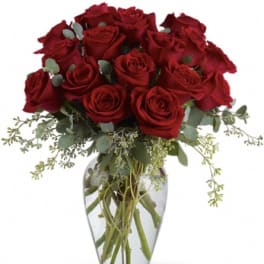 Red roses arranged in a clear glass vase with eucalyptus