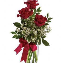 Red roses in a clear glass vase with a red ribbon