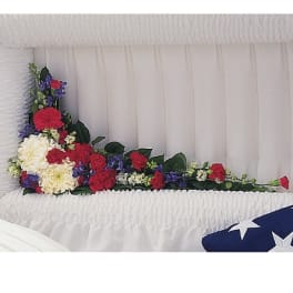 Red, white, and purple flowers arranged in a white casket