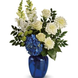 White and blue floral arrangement in a cobalt vase