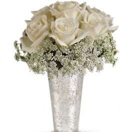 White roses in a clear glass vase with baby's breath