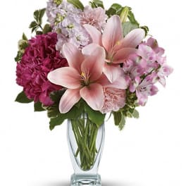 Pink lilies and mixed pink flowers in a clear glass vase
