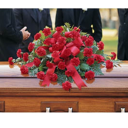 Red carnation spray with ribbon on a wooden casket