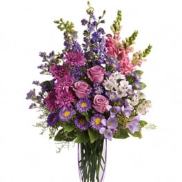 Purple and pink mixed flower arrangement in a clear vase