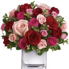 Bouquet of red, pink, and blush roses in a clear glass vase