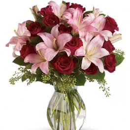Bouquet of pink lilies and red roses in a clear glass vase
