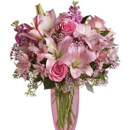 Pink lilies and roses in a pink glass vase