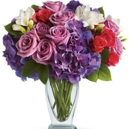 Bouquet of purple, pink, red, and white flowers in a clear glass vase