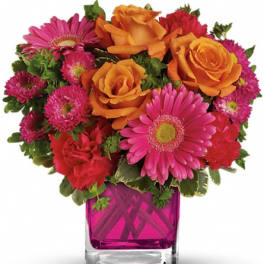 Bouquet of orange roses and pink daisies in a magenta glass vase