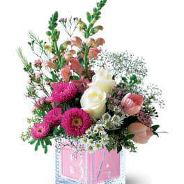 Pink and white floral arrangement in a pink baby block vase