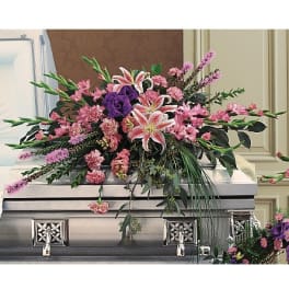 Pink and purple floral spray arranged on a silver casket