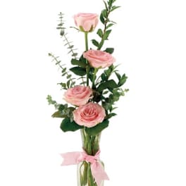Pink roses in a clear glass vase with a pink ribbon