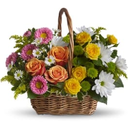 Basket of pink, yellow, and white flowers with a woven handle