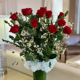 Red roses and white hydrangeas in a tall glass vase