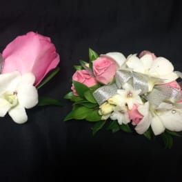 Pink and white floral corsages with silver ribbon on a black background