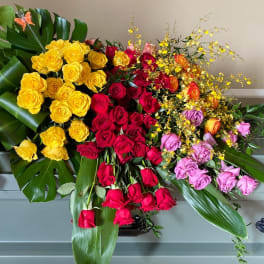 Large arrangement of multicolored roses with tropical leaves