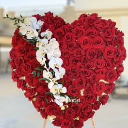 Heart-shaped red rose arrangement with white orchids on an easel
