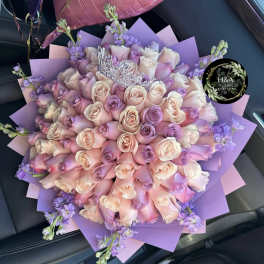 Bouquet of pink and lavender roses wrapped in purple paper