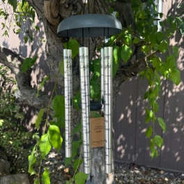 Silver wind chime hanging from a tree branch