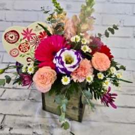 Mixed bouquet in a wooden box with pink, peach, and purple flowers