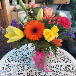 Colorful mixed bouquet in a glass vase with a pink ribbon