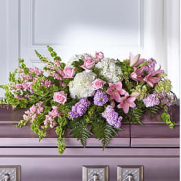 Pastel pink and white casket spray with roses, lilies, and hydrangeas on a lavender casket.