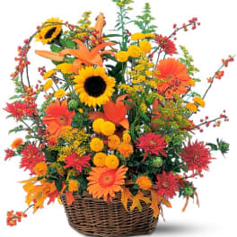 Autumn flower arrangement in a wicker basket with sunflowers and orange blooms