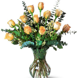 Yellow roses arranged in a clear glass vase with eucalyptus