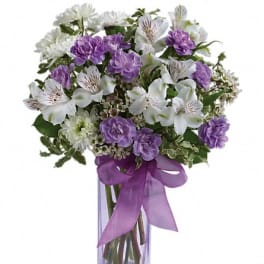 Purple and white bouquet in a clear glass vase with a purple ribbon