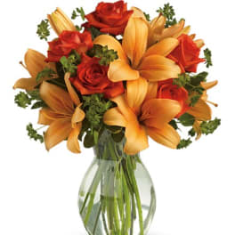Orange lilies and red roses in a clear glass vase