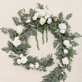 Large open wreath of cascading greenery with white roses and peonies and a touch of peach blooms