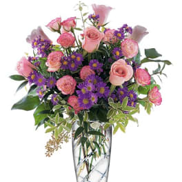 Pink roses and purple daisies in a clear glass vase