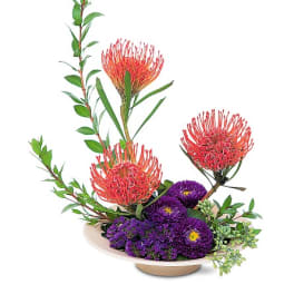 Purple and red floral arrangement in a low dish