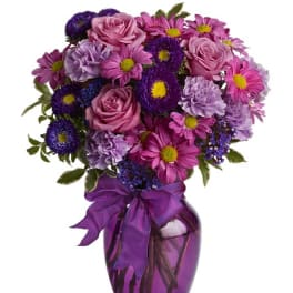 Pink and purple mixed bouquet in a purple vase with ribbon