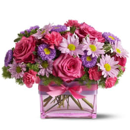 Pink roses and purple daisies in a square glass vase with a ribbon