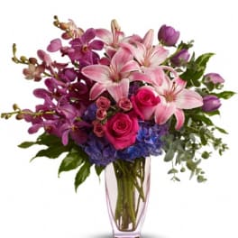 Pink lilies, roses, orchids, and hydrangeas in a clear vase