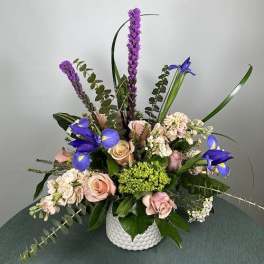 Mixed bouquet of pink roses and purple irises in a white vase