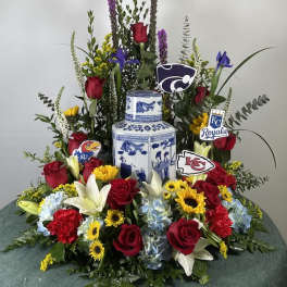 Large floral arrangement with roses, lilies, and sunflowers around a blue-and-white vase