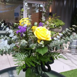Yellow roses with purple flowers and eucalyptus in a vase