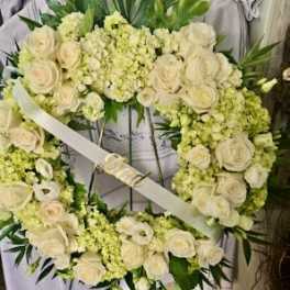 White floral wreath with roses and pale green blooms on a stand