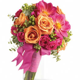Bouquet of orange and pink flowers in a clear glass vase with a ribbon