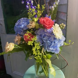 Mixed bouquet with hydrangeas, roses, and daisies in a glass vase
