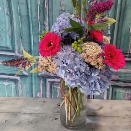 Bouquet of blue hydrangeas and bright pink gerbera daisies in a glass vase