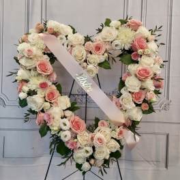 Heart-shaped floral wreath of pink and white roses with a pink ribbon